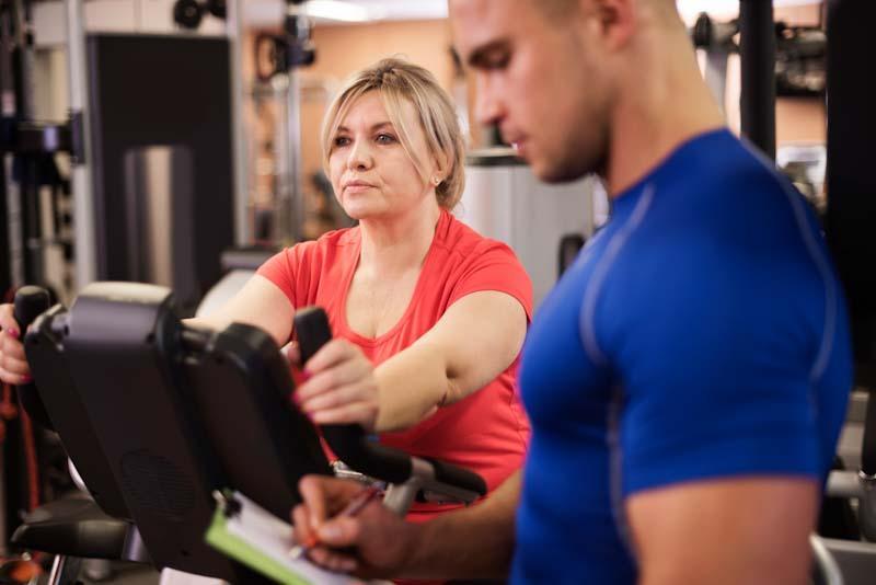 A personal trainer makes some notes about his client's performance. Learn about becoming a personal trainer at EliteTrainr.com.