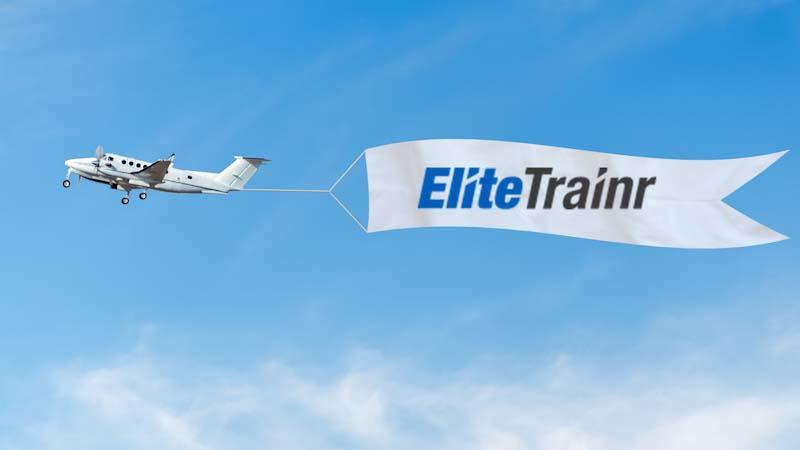 A plane pulls a banner with the Elite Trainr name. Learn about promoting your personal training business at EliteTrainr.com.