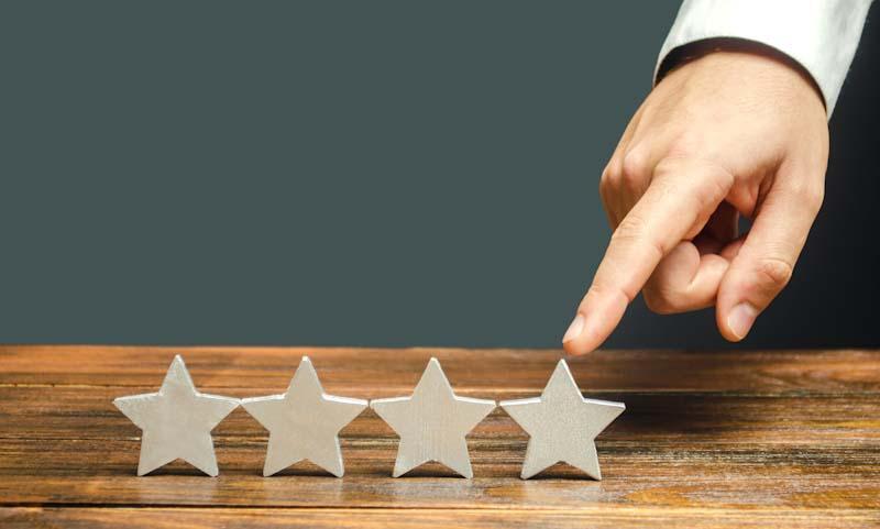 A representative image showing four stars with a hand pointing to the fourth, symbolizing the need to achieve high ratings from personal training clients.