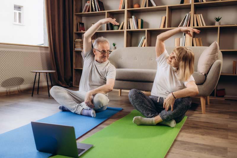 An elderly couple with diabetes exercises in their living room with their personal trainer recommended workout on the EliteTrainr app.