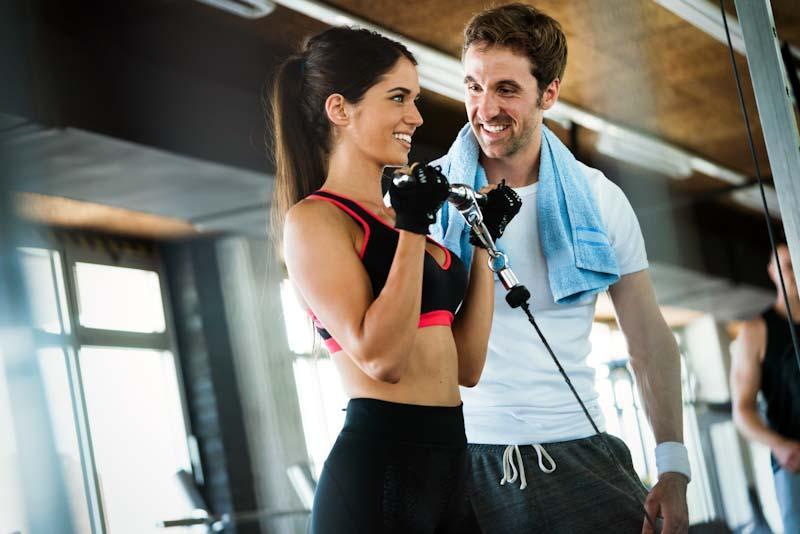 A personal trainer happily works with a client he got from his marketing campaign. Learn about marketing your personal trainer business at EliteTrainr.com.