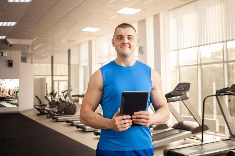 A personal trainer proudly holds his tablet that he uses with the Elite Trainr app to manage his fitness clients. Learn more at EliteTrainr.com.