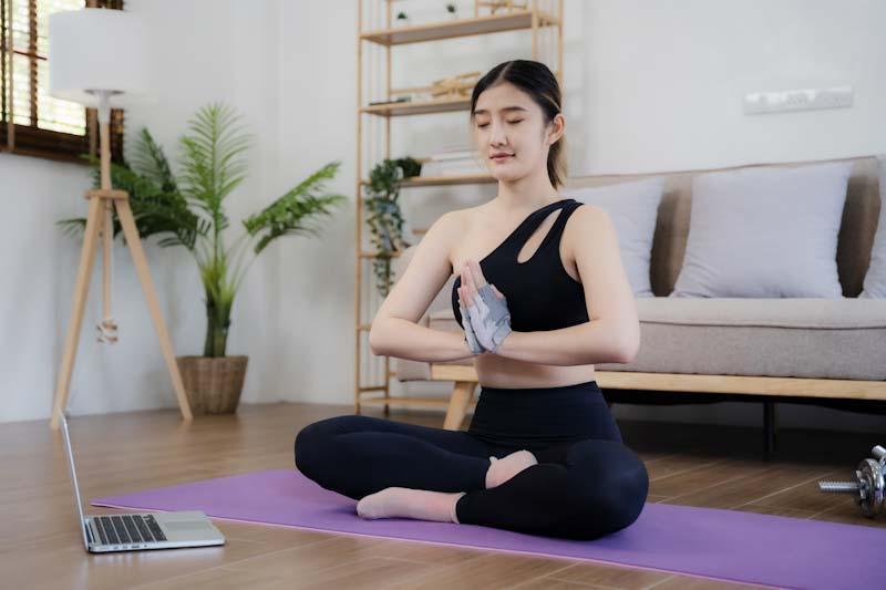A personal trainer demonstrates a yoga pose online to her clients. Learn about managing your fitness clients at EliteTrainr.com.