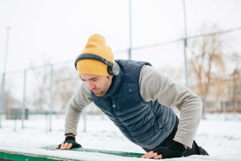 A man works out while outside in winter. Learn about the best winter workouts for your fitness clients at EliteTrainr.com.