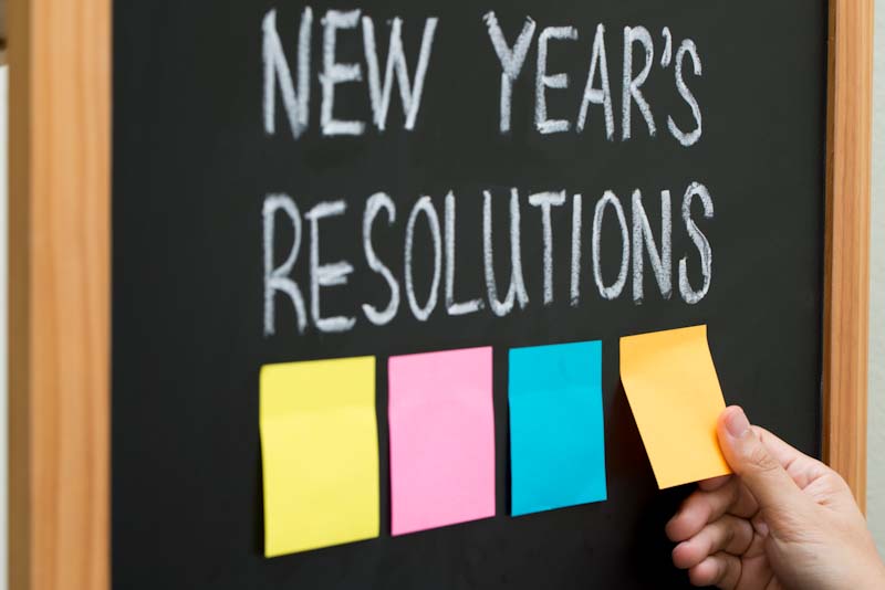A chalkboard with New Year's Resolutions and sticky notes on it. 