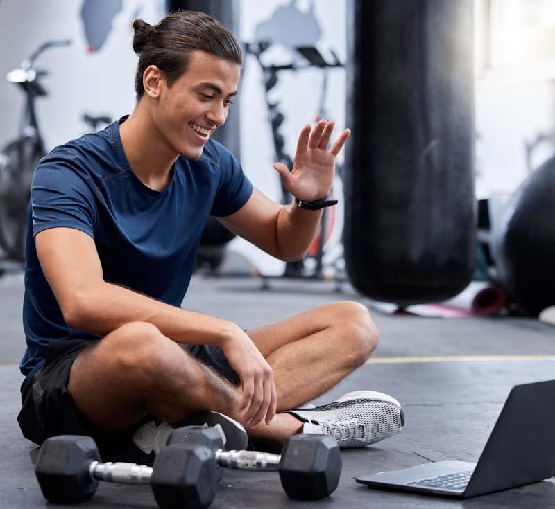 A personal trainer waves hello to his online client. Learn how you can grow your training business online at EliteTrainr.com.