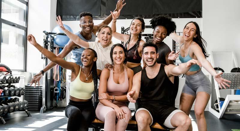 A happy community of fitness trainers is shown celebrating their online success. Learn more about building a thriving online training community to launch your success at EliteTrainr.com.